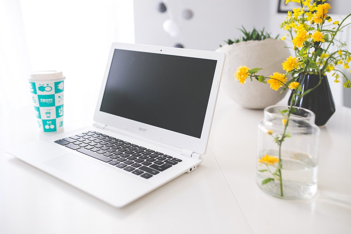 Lys arbeidsplass med laptop og kaffekopp – du kan sjekke egne anmerkninger gratis hos kredittopplysningsbyråene.