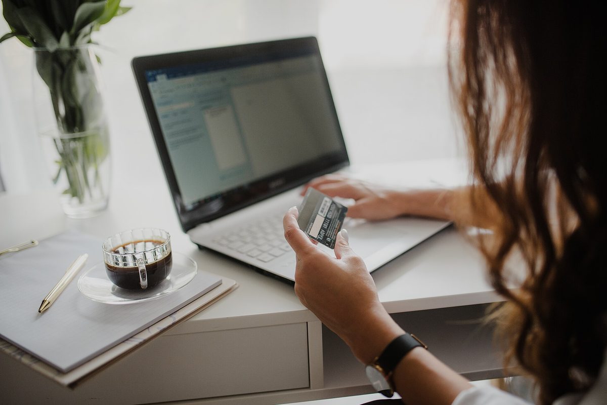 Bankkort i hånden foran laptopen – netthandel på kreditt er få tastetrykk unna, og en kredittsperre legger inn en naturlig pause.