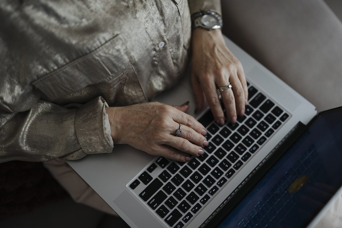 Hender på tastaturet til en laptop hjemme i sofaen – du kan gratis kredittsjekke deg selv hos byråene på nett.